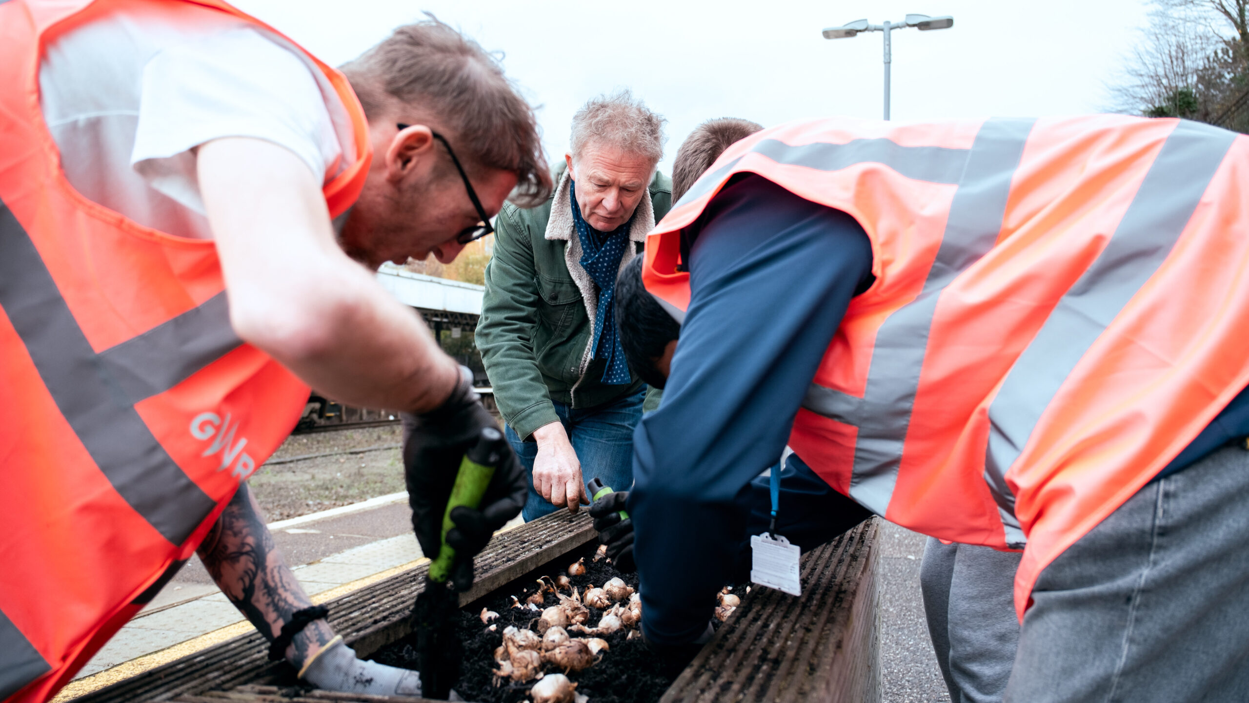 People plant flowers at a train station