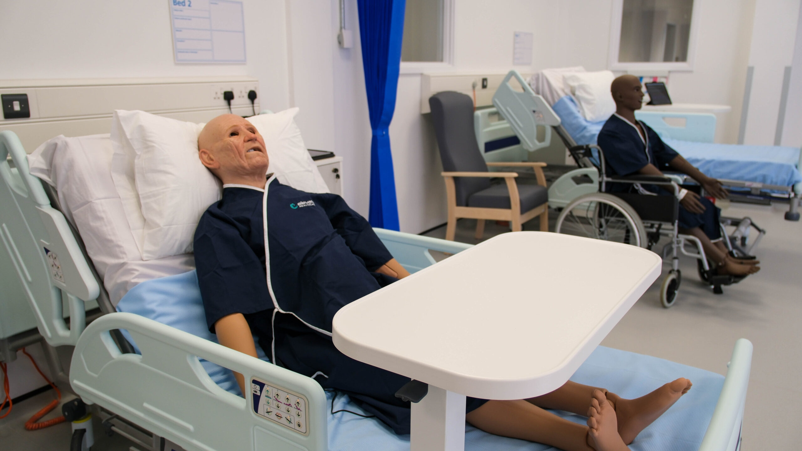Hospital training mannequin in a bed in a hospital ward.  