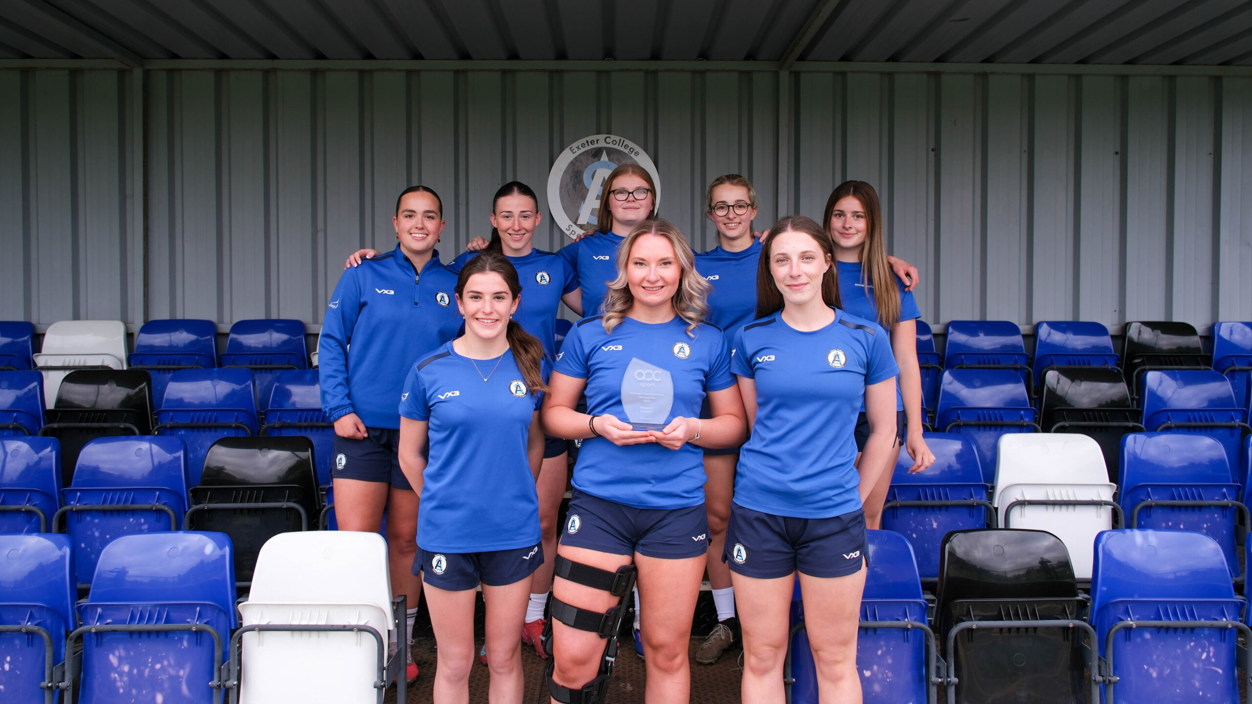 Ten Exeter College football players hold up a trophy 