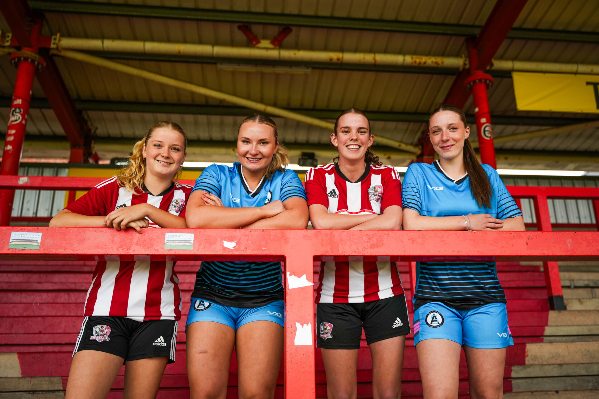 Four academy football players stand together in a stadium