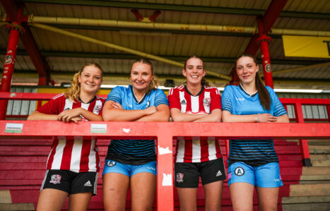 Four academy football players stand together in a stadium