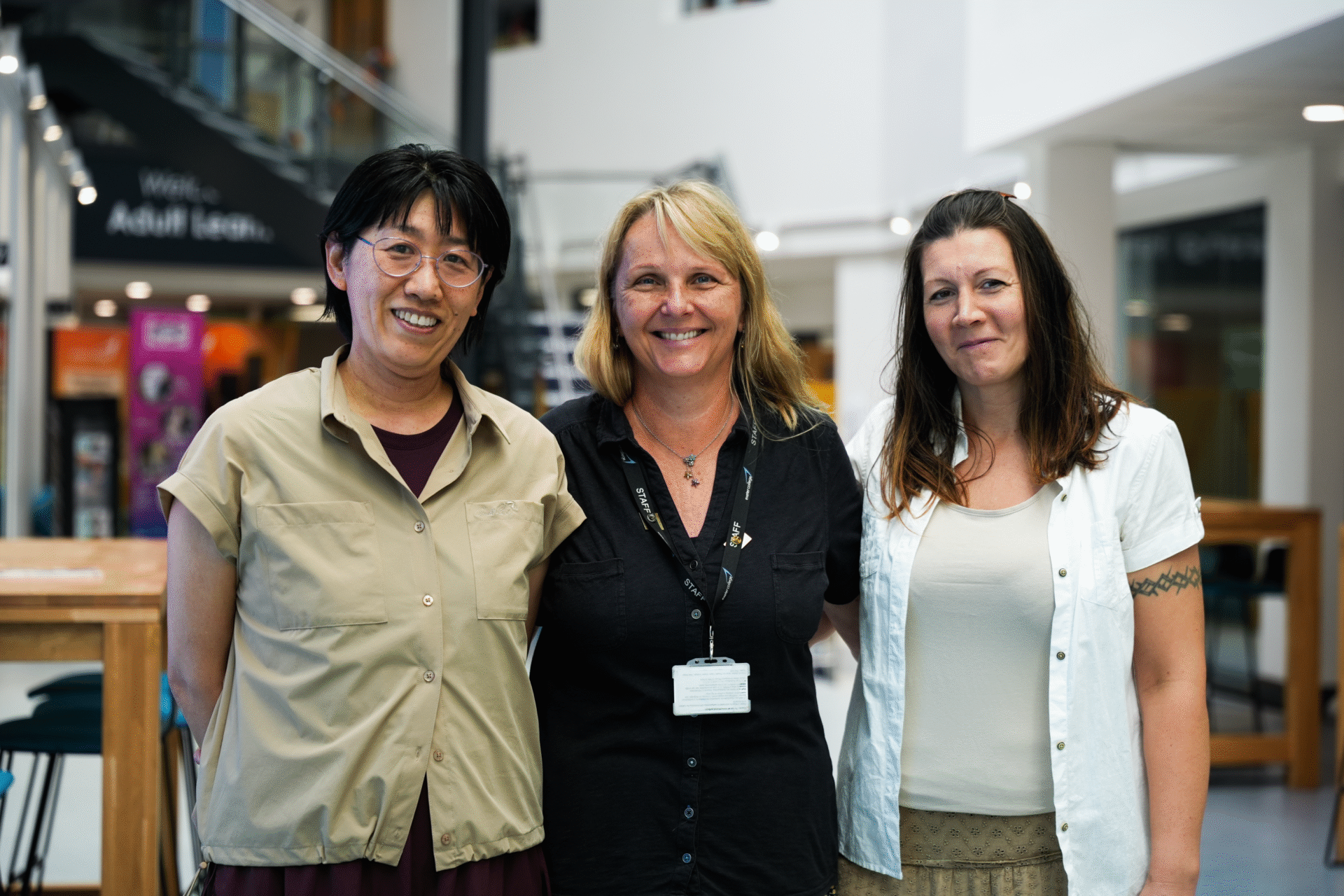 Three adult learners at Exeter College hugging