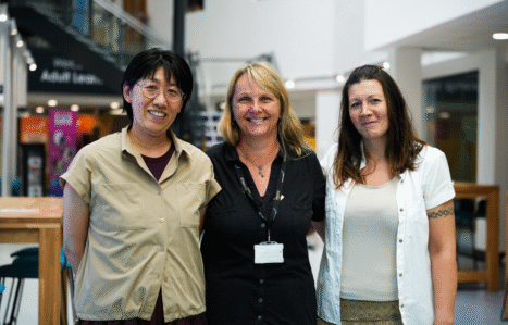 Three adult learners at Exeter College hugging